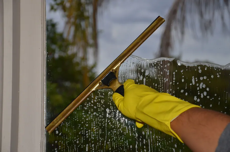 A service example: a gloved hand squeegeeing soapy window glass